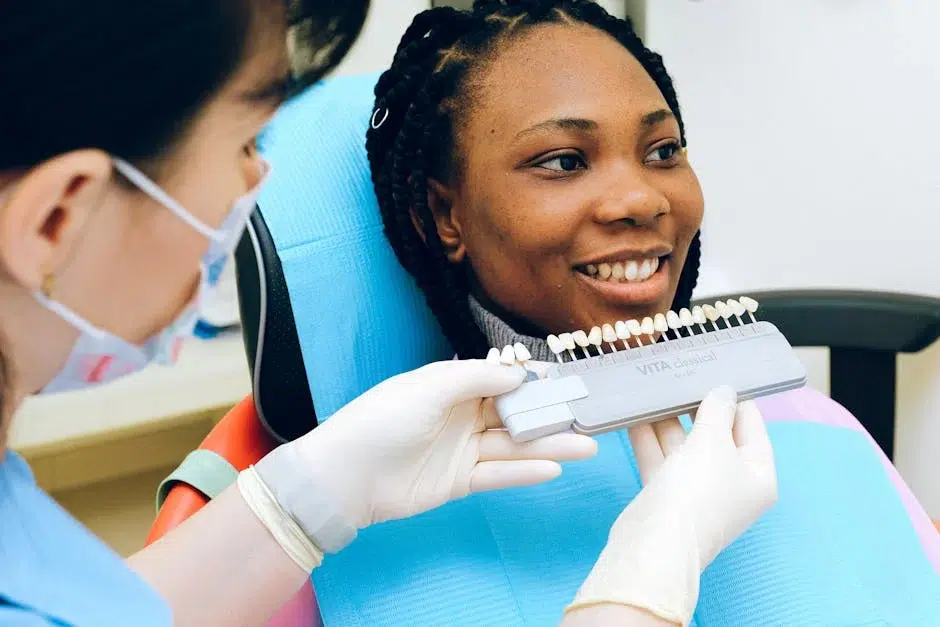 Dentist holding a shade guide to a smiling patient's teeth