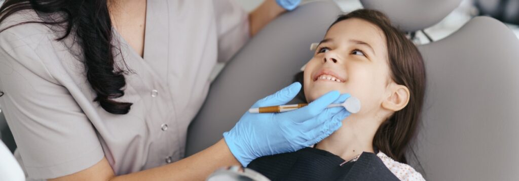 Dental hygienist examining a smiling girl's teeth