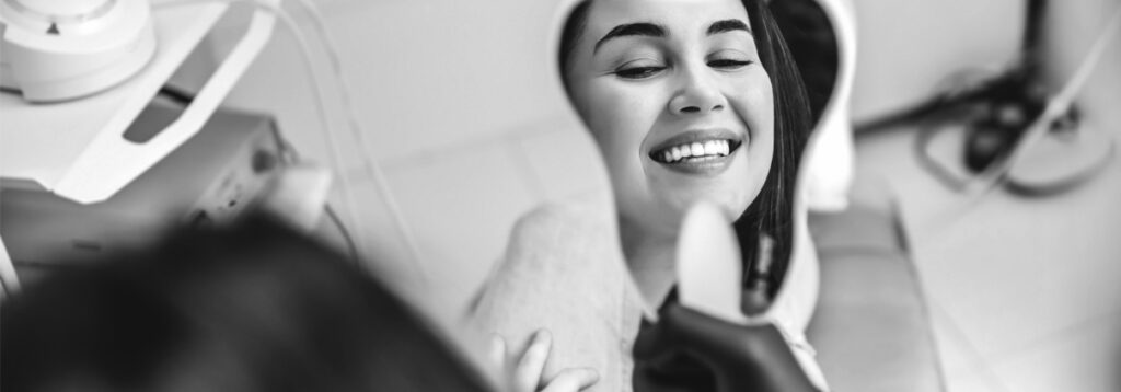 Woman smiling in a dental chair while a dentist works