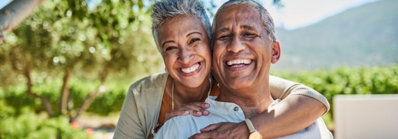 Smiling older couple embracing outdoors — Choosing the Right Dentures: A Guide for Fort Collins Patients