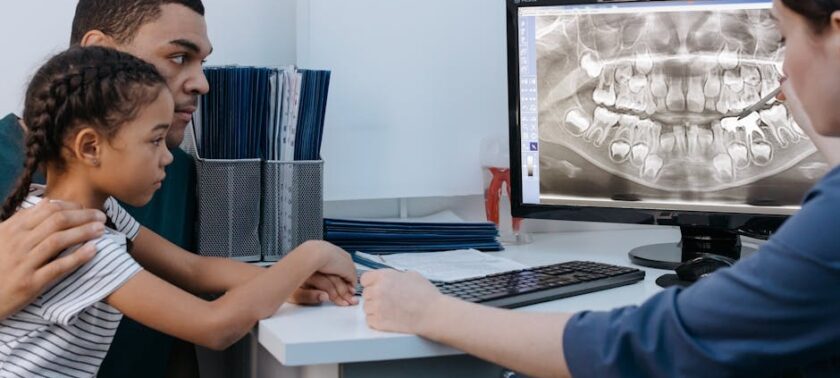 Dentist showing a parent and child a dental X-ray on screen