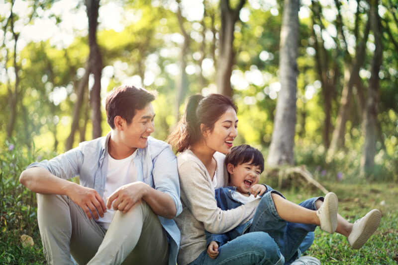 Family sitting together in the grass in a sunny forest