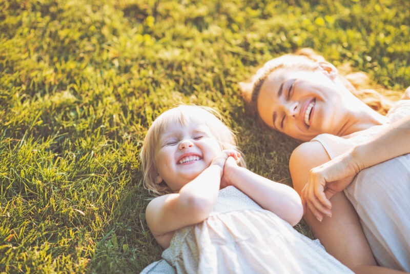 Mother and young daughter laughing in the grass