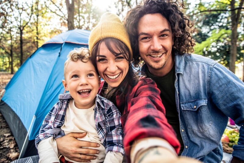 Family taking a selfie in front of their tent while camping
