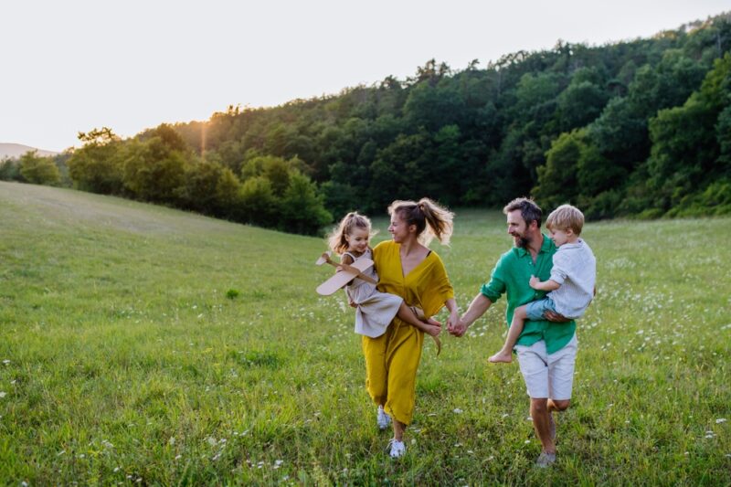 Family running hand in hand across a green meadow