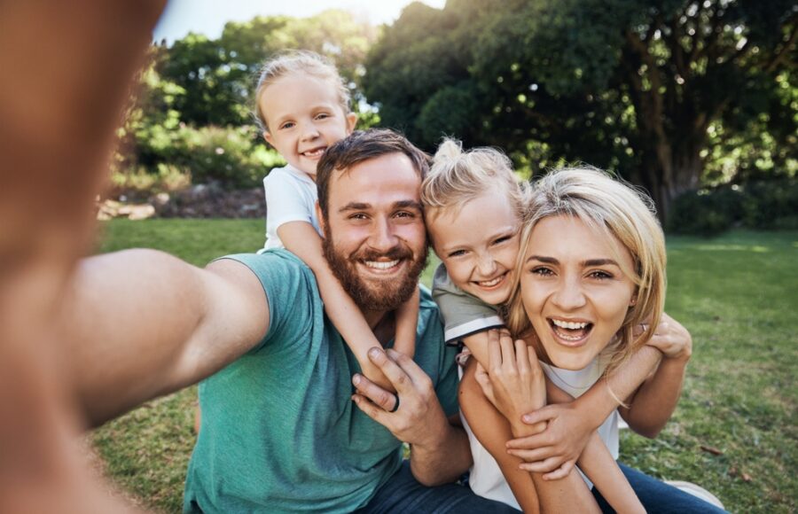 Family of four taking a smiling selfie outdoors